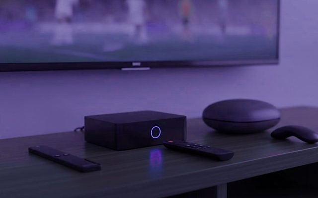Cover for “Best IPTV box or stick: choosing what to plug in behind the TV”: a set-top box, a round streaming box and two remotes on a TV console, with a match on the screen above