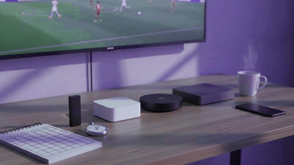 Cover for “Best IPTV service? Eight questions to ask any provider before you pay”: a streaming stick, small streaming boxes, a notepad and a coffee mug on a TV console while a football match plays